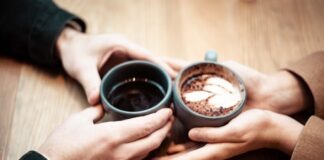 two person holding ceramic mugs with coffee