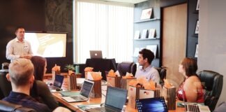 man standing in front of people sitting beside table with laptop computers