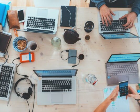 people sitting down near table with assorted laptop computers