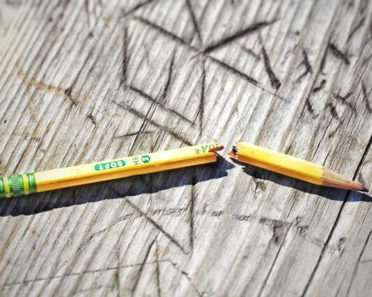 yellow pencil on gray wooden surface