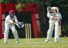 man in white and red jersey shirt and white pants holding brown wooden stick