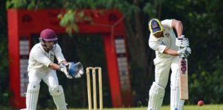 man in white and red jersey shirt and white pants holding brown wooden stick