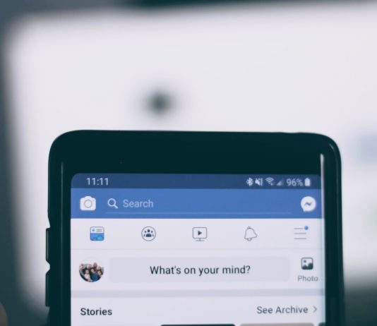 person holding smartphone using facebook account