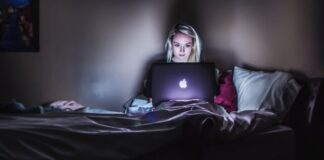 woman sitting on bed with MacBook on lap