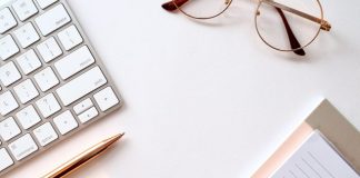 pen near black lined paper and eyeglasses