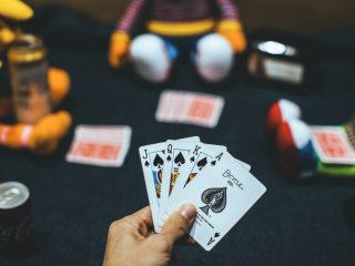 лице кое држи карти за играње во близина на црвено-белата топка