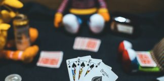 person holding playing cards near red and white ball