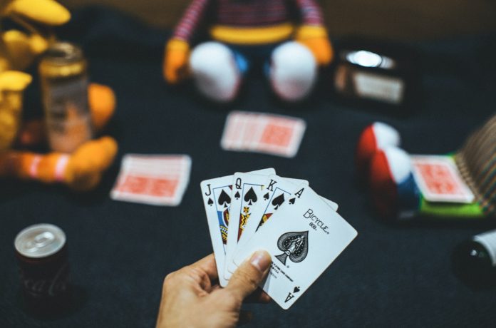 Photo by Kin Li person holding playing cards near red and white ball