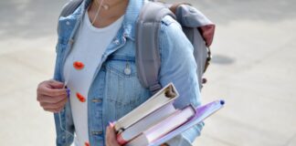 woman wearing blue denim jacket holding book