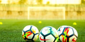 three white-and-black soccer balls on field