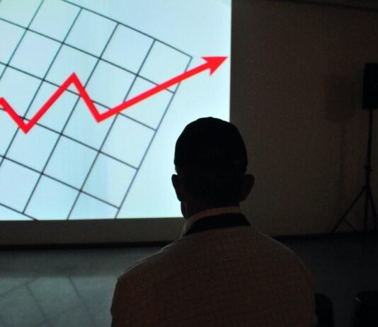 bambo wovala pamwamba woyera akuyang'ana pa projekita graph screen