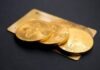 three round gold-colored Bitcoin tokens