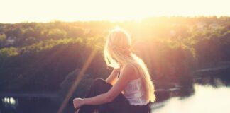 woman sitting on brown surface watching at body of water