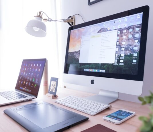 silver iMac near iPhone on brown wooden table