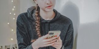 woman in black sweater holding white smartphone