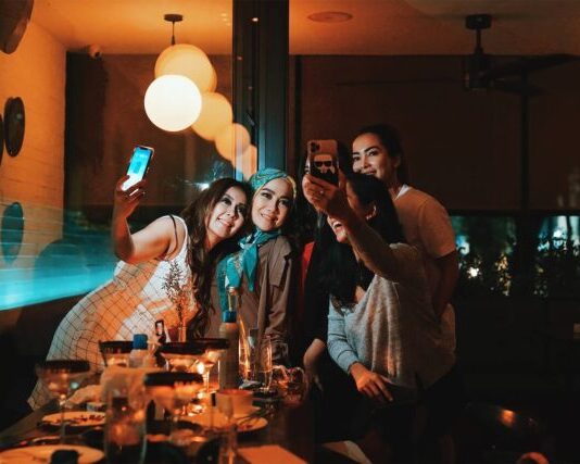 3 women smiling and standing near table