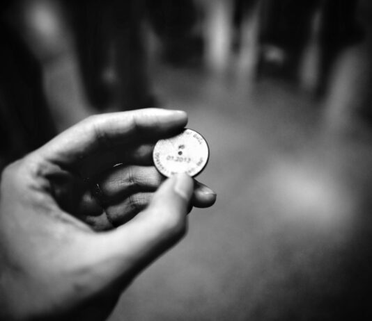 grayscale photography of person holding coin