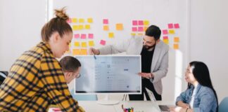 man standing behind flat screen computer monitor