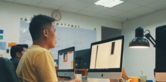 man using Apple desktop inside room beside man