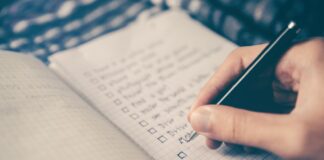 person writing bucket list on book
