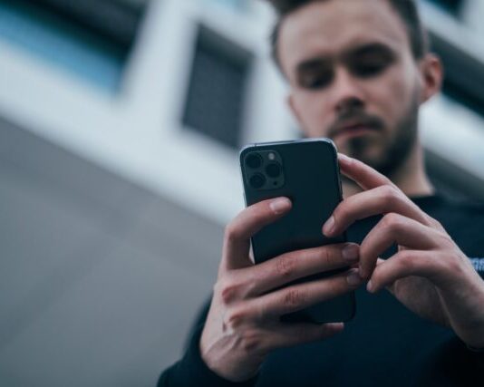 lalaki nga nagsul-ob og itom nga sweater gamit ang smartphone