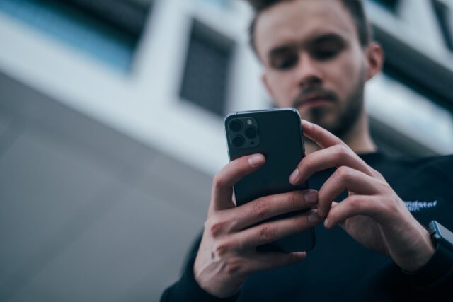 Photo by Jonas Leupe man wearing black sweater using smartphone