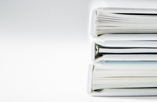 A stack of thick folders on a white surface