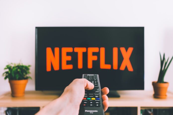 Photo by freestocks person holding remote pointing at TV