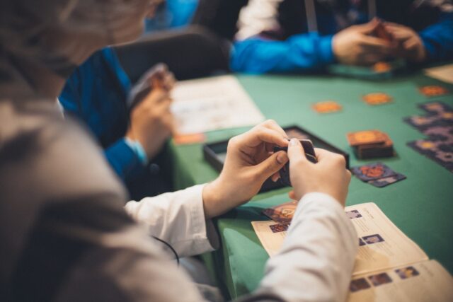 Photo by Olga Fedina Crop people playing cards at table