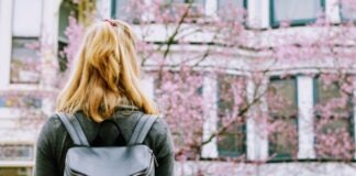 woman wearing backpack facing concrete building