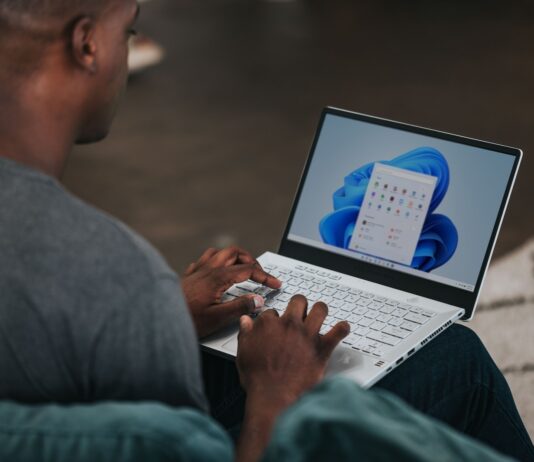man in gray long sleeve shirt using Windows 11 computer