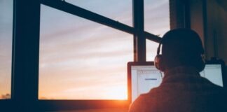 man sitting facing monitor