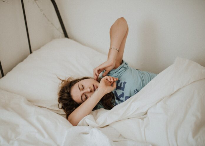 Photo by Kinga Howard woman covered in white blanket sleeping on white bed comforter
