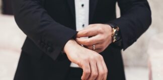 A man's hands adjusting the cuffs of his black suit