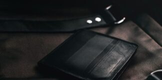 black leather bifold wallet on brown textile