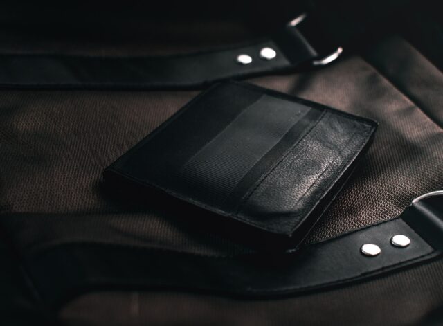 black leather bifold wallet on brown textile