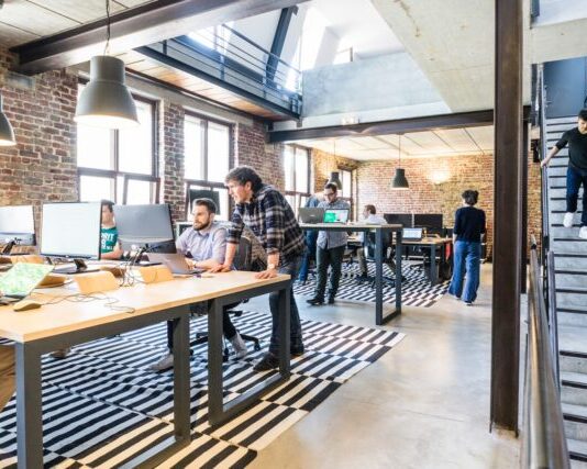 man standing beside another sitting man using computer