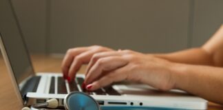 person sitting while using laptop computer and green stethoscope near
