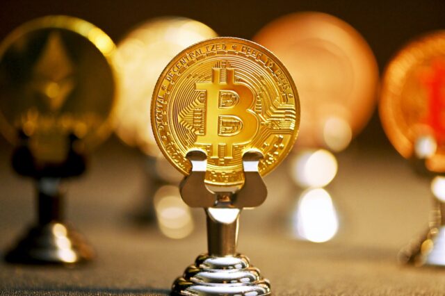 Photo by Kanchanara a bitcoin on a stand in front of other bitcoins