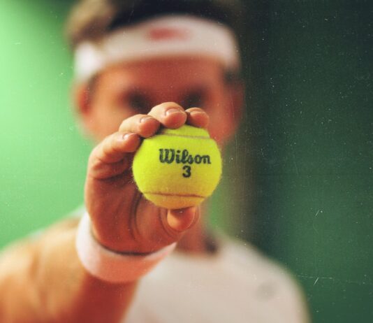 person holding green Wilson tennis ball