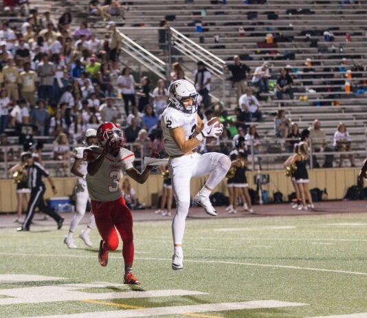 man catching brown football on stadium