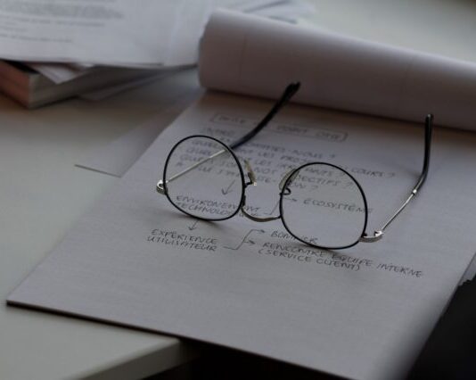 black framed eyeglasses on top of white printing paper