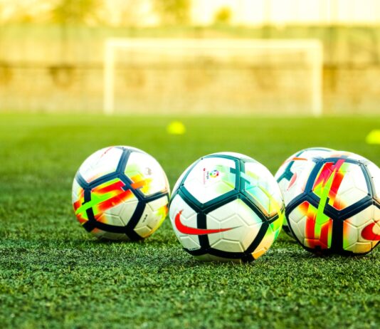 three white-and-black soccer balls on field