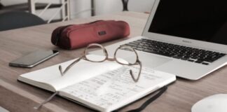 eyeglasses on book beside laptop