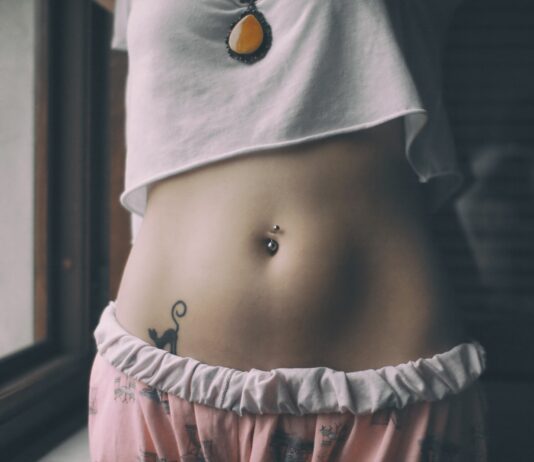 woman in white crop shirt with tattoo on her belly
