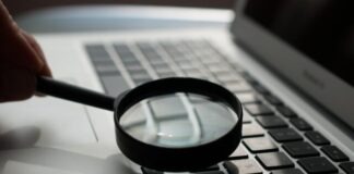 magnifying glass near gray laptop computer