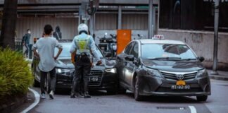man in white and black stripe shirt and black pants standing beside black car during daytime