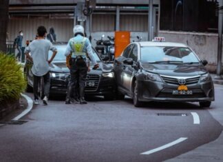 man in white and black stripe shirt and black pants standing beside black car during daytime