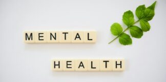 the word mental health spelled with scrabbles next to a green leaf