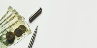 gray pen beside coins on Indian rupee banknotes